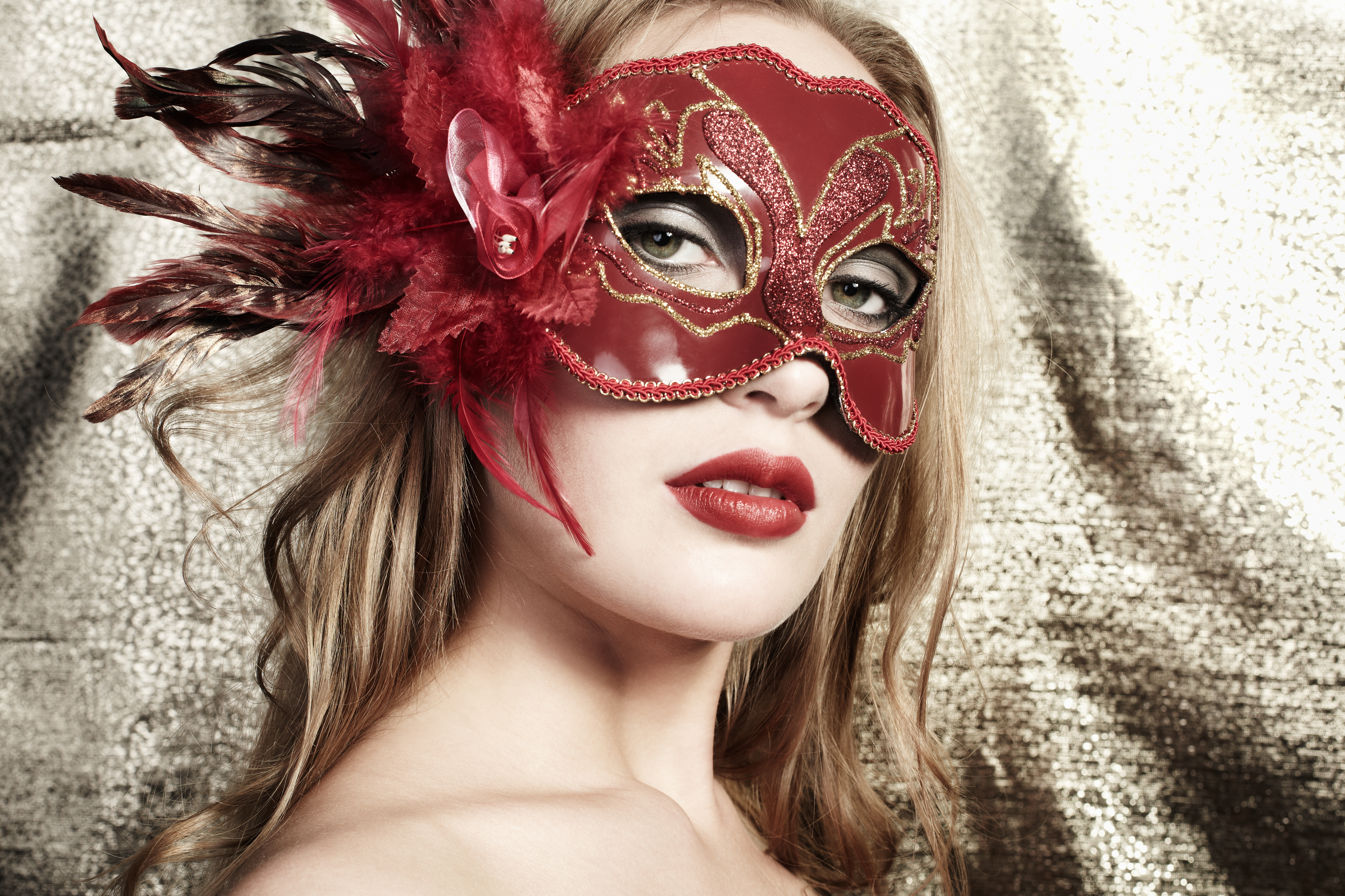Beautiful young woman in a red mysterious venetian mask on a gol